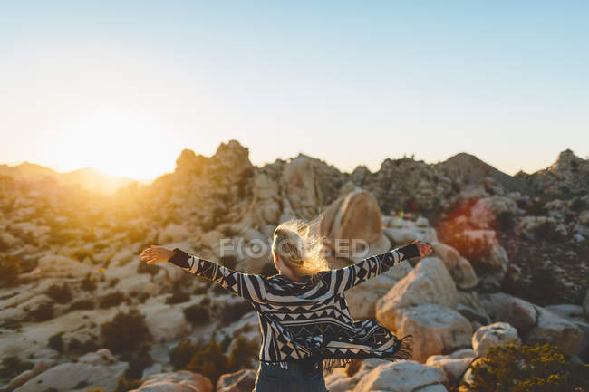Женщина, расправляющая руки в Национальном парке Джошуа Три, смотрит на вид — стоковое фото