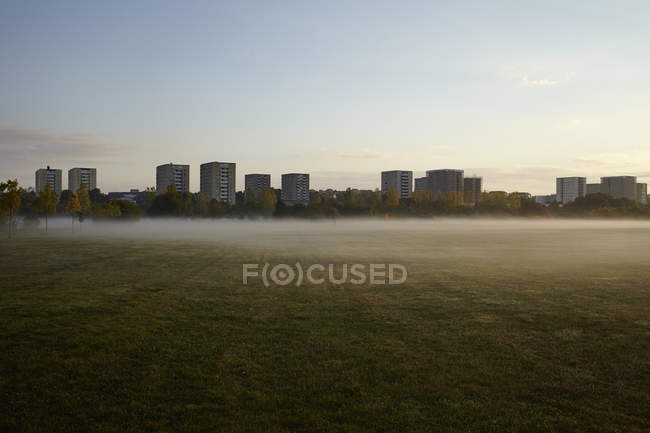 Foggy field and blocks of flats in background — Stock Photo