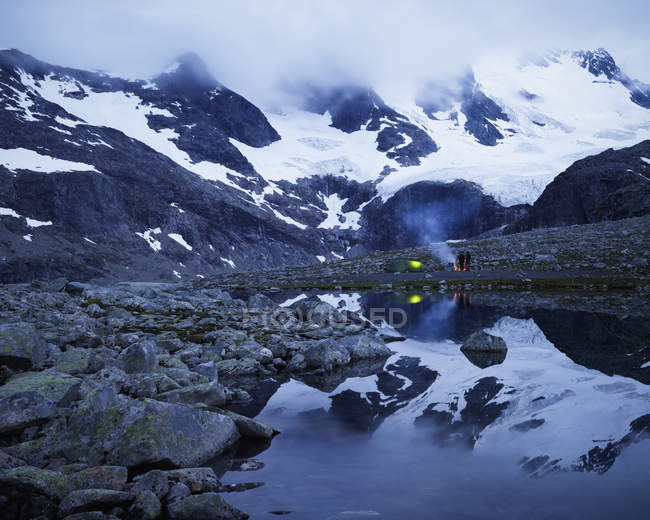 Scenic view of Jotunheimen range with Sentraltind peak, couple camping in background — Stock Photo