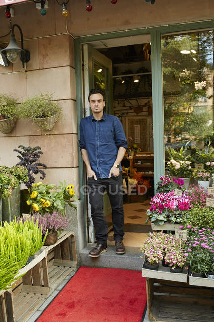 Florist standing in front of entrance of flower shop — Stock Photo