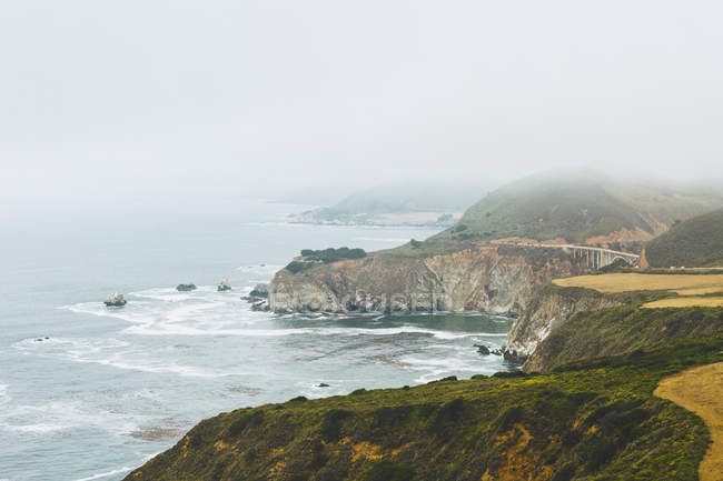 Vista aerea della costa rocciosa con ponte in lontananza — Foto stock