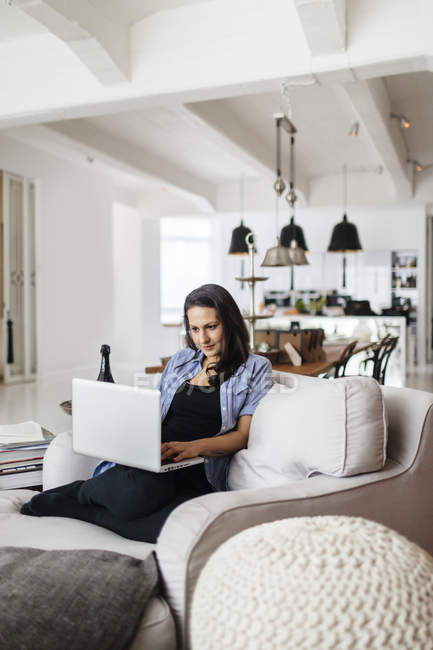 Жінка використовує ноутбук у вітальні, вибірковий фокус — стокове фото