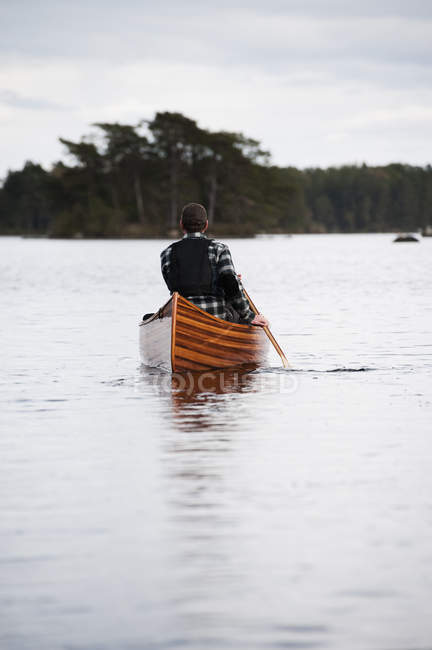 Людина дитячий дерев'яні каное на озері — стокове фото