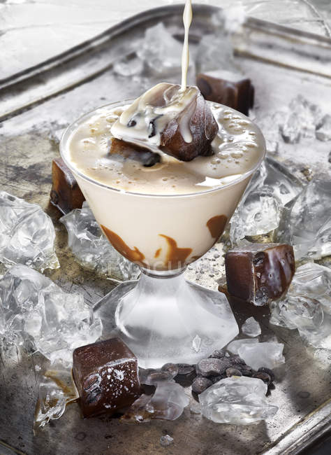 Cream splashing in glass of ice coffee cocktail — Stock Photo