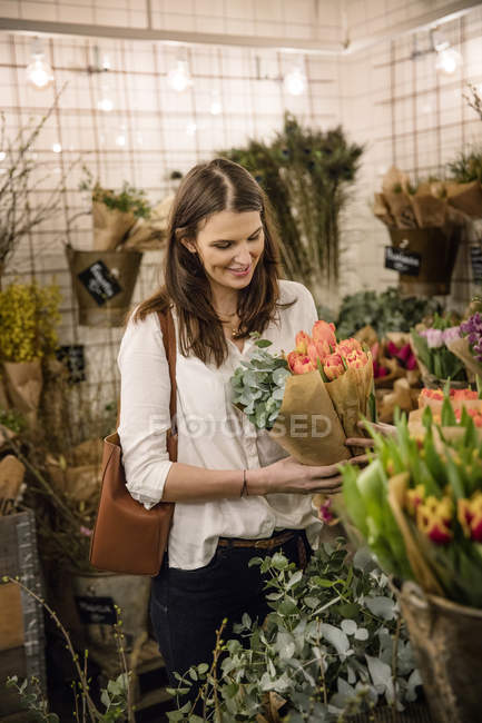Femme choisissant des fleurs dans la boutique, foyer sélectif — Photo de stock