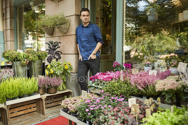 Флорист, стоящий перед входом в цветочный магазин — стоковое фото