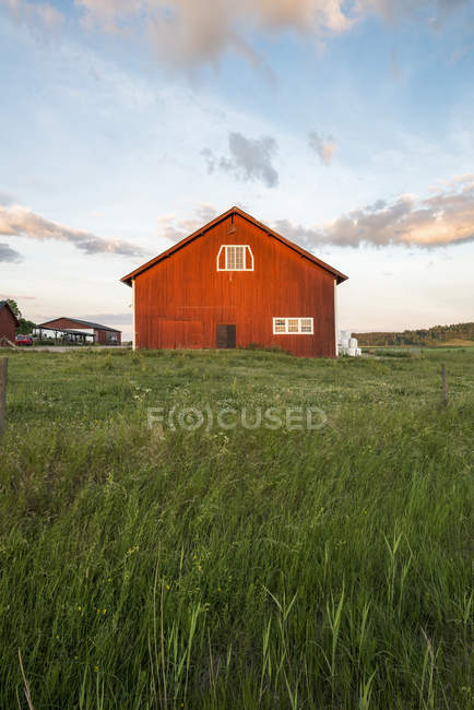 Blue sky with clouds over cottage in field — Stock Photo