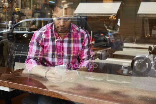 Зрілий чоловік перевіряє мобільний телефон всередині кафе — стокове фото