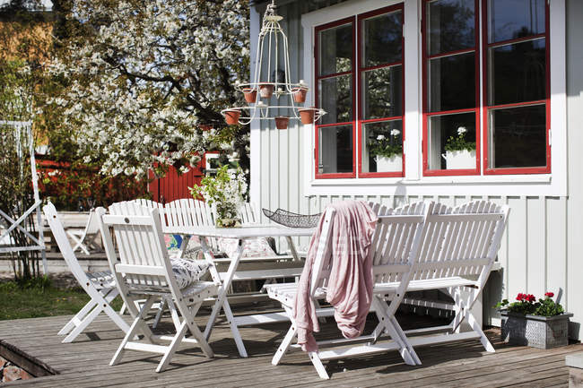 Mesa blanca y sillas en patio de madera - foto de stock