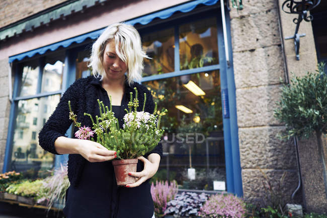 Флорист держит горшок с растением против внешнего вида здания — стоковое фото