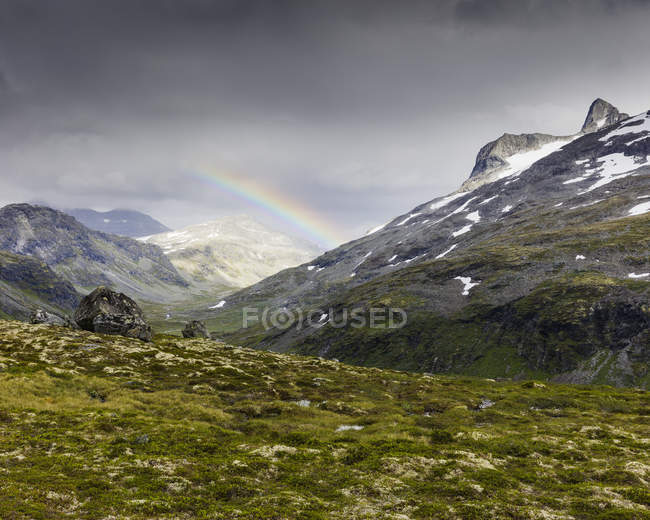 Jotunheimen gamme et luxuriante vallée verte avec arc-en-ciel dans le ciel — Photo de stock