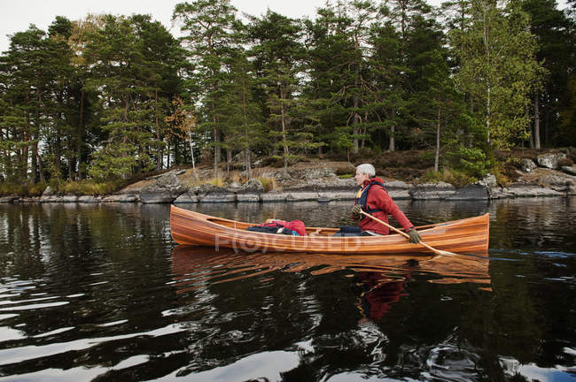 Vista lateral de homem remando canoa no lago — Fotografia de Stock