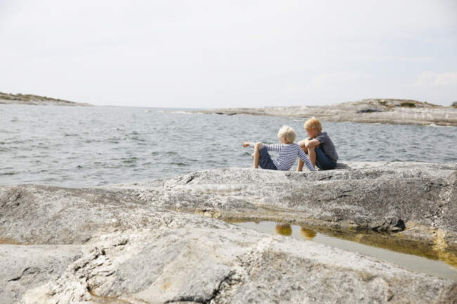 Два мальчика сидят на скалистом берегу на Стокгольмском архипелаге — стоковое фото