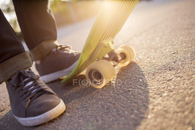 Männerfüße mit Skateboard im grellen Sonnenlicht — Stockfoto