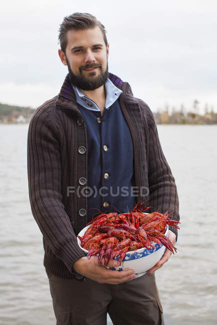Retrato del hombre adulto medio sosteniendo un tazón de cangrejos de río - foto de stock