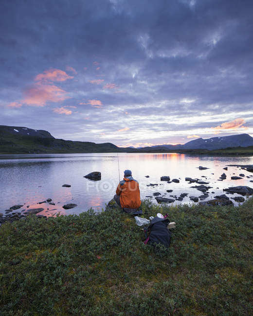 Man fishing in lake Sjuendevatnet at sunset — Stock Photo
