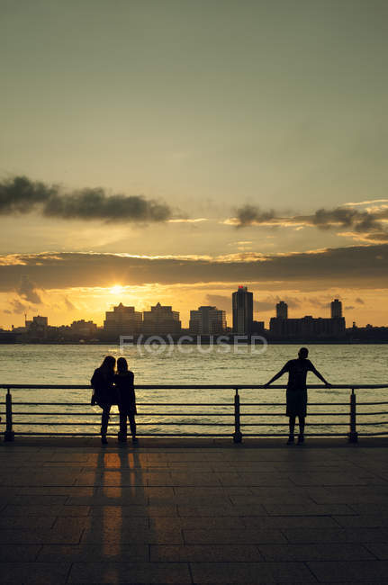 Gente mirando el horizonte de Manhattan al atardecer - foto de stock
