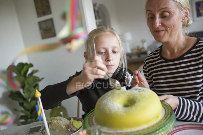 Menina e mulher madura corte bolo de aniversário, foco diferencial — Fotografia de Stock