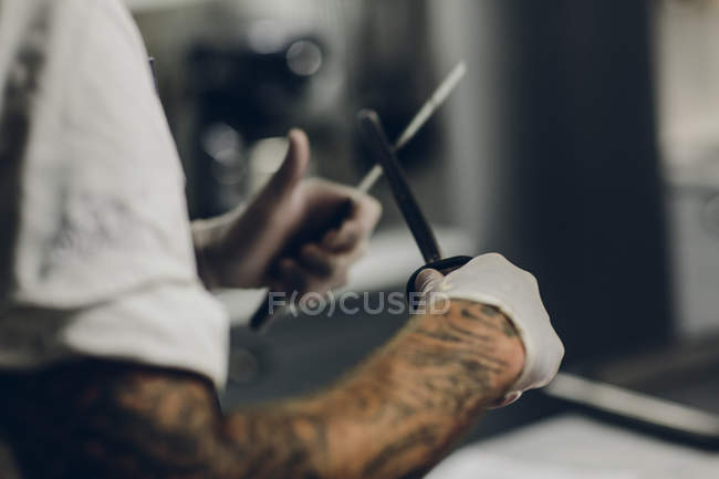 Мясник точит нож, дифференциальная фокусировка — стоковое фото