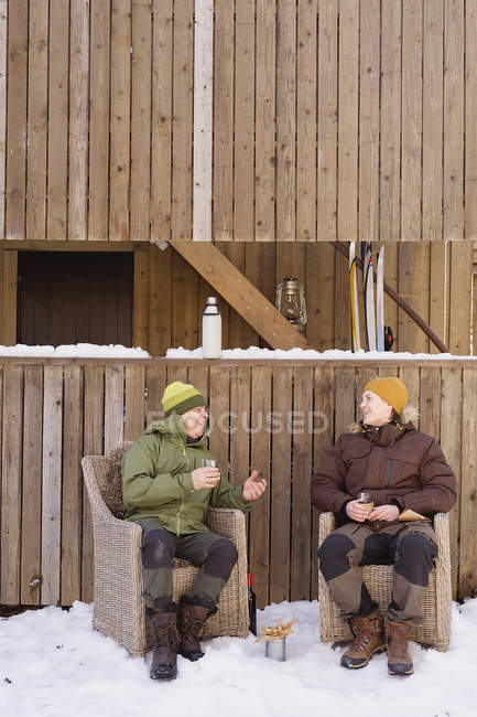 People relaxing in front of wooden house — Stock Photo