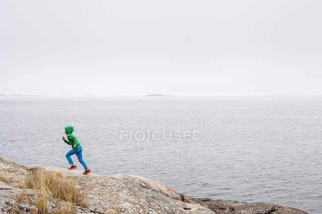 Ragazzo che corre vicino al lago, attenzione selettiva — Foto stock