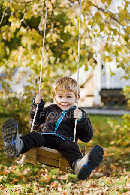 Мальчик играет на качелях в саду, избирательный фокус — стоковое фото