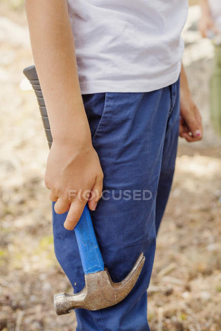 Mid section of boy holding hammer, selective focus — Stock Photo
