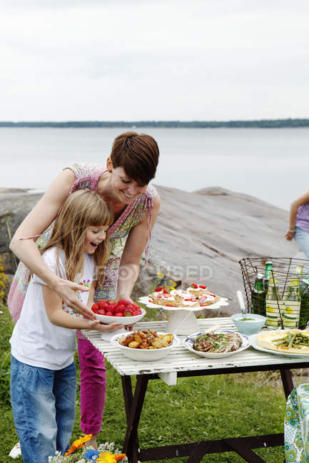 Frau bereitet Picknicktisch am Meer zu — Stockfoto