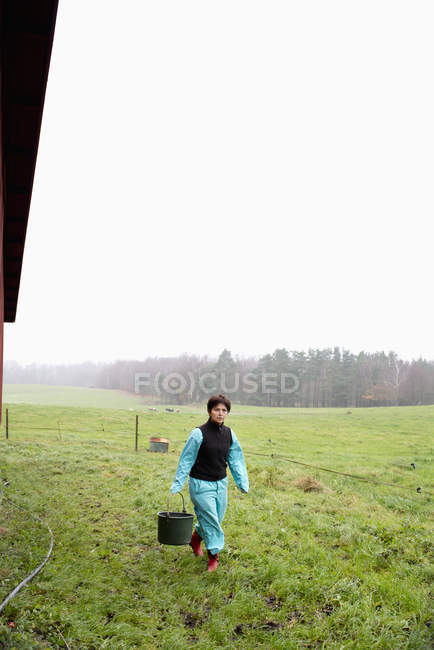 Portrait of farmer carrying bucket at field — Stock Photo