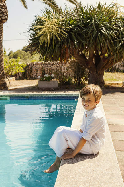 Мальчик сидит на краю бассейна отеля — стоковое фото