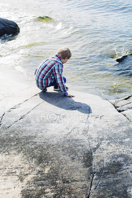 Niño tocando agua fría del mar, enfoque selectivo - foto de stock