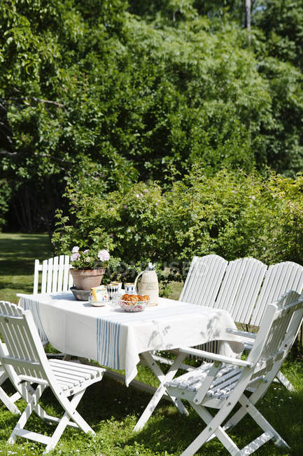 Белый стол и стулья в саду летом — стоковое фото