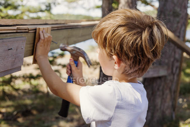 Side view of boy pounding hammer — Stock Photo