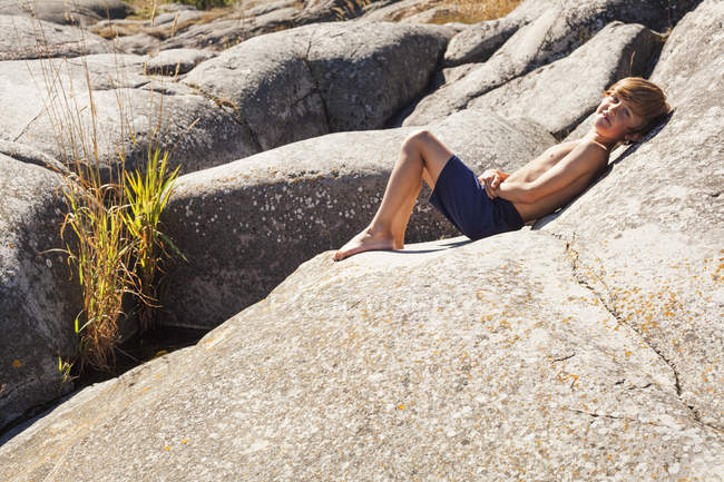 Хлопчик розслабляється на великому камені, вибірковий фокус — стокове фото