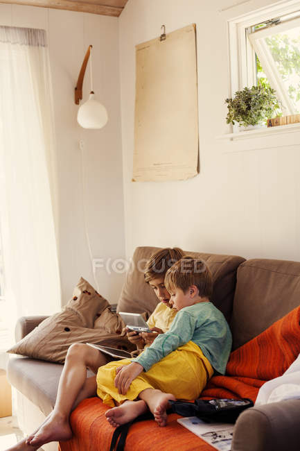 Брати граючи на ігровому консолі на дивані, вибіркового фокусування — стокове фото