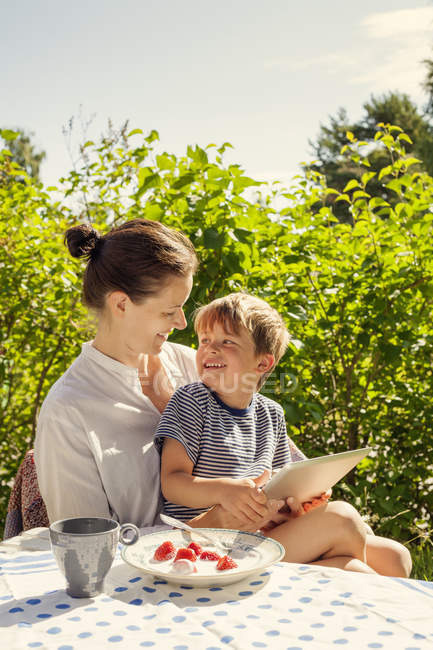 Retrato de filho e mãe usando tablet digital no jardim — Fotografia de Stock