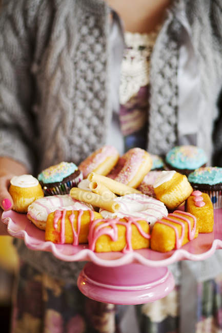 Женщина держит торт стенд с красочным печеньем — стоковое фото