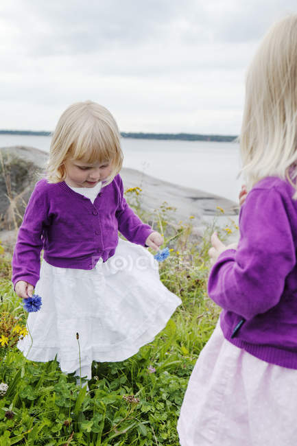 Zwillingsmädchen spielen am Meer, Fokus auf Vordergrund — Stockfoto