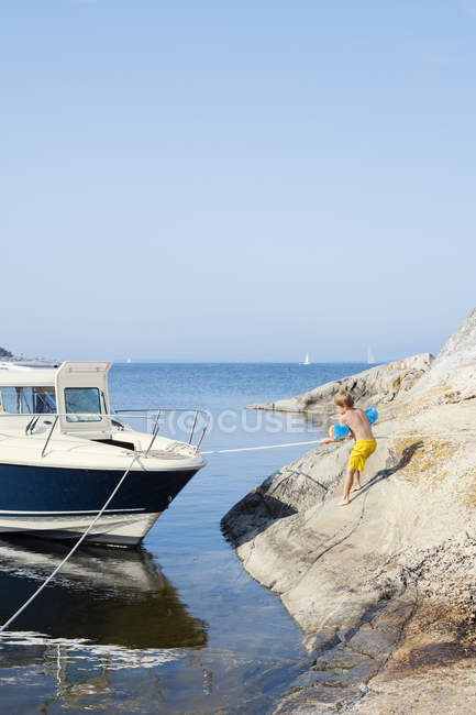 Menino de pé na rocha por veleiro no mar — Fotografia de Stock