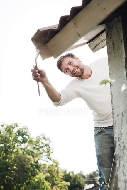 Uomo sorridente pittura tetto, messa a fuoco selettiva — Foto stock