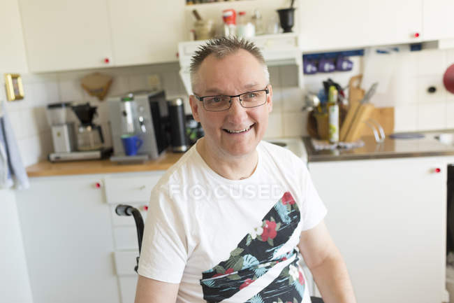 Homme en fauteuil roulant dans la cuisine regardant la caméra — Photo de stock