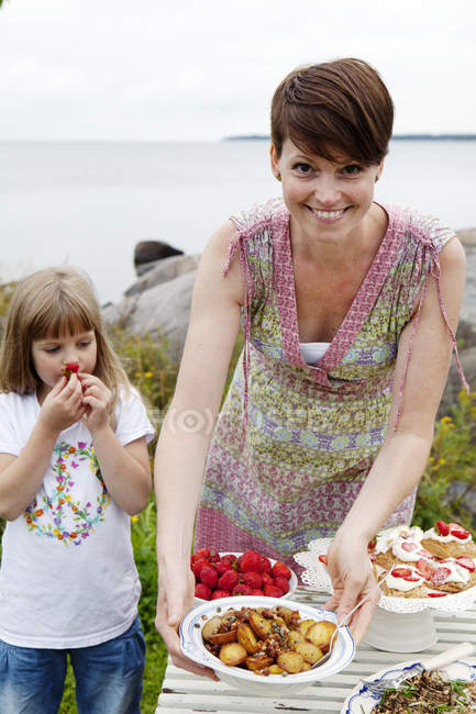 Mulher preparando mesa de piquenique à beira-mar — Fotografia de Stock
