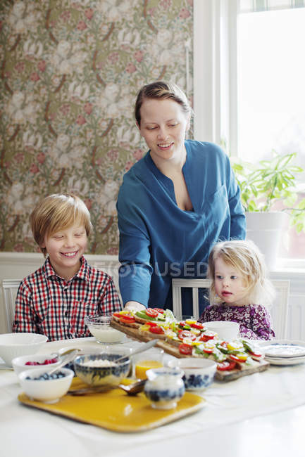 Mère avec deux enfants petit déjeuner dans la salle à manger — Photo de stock