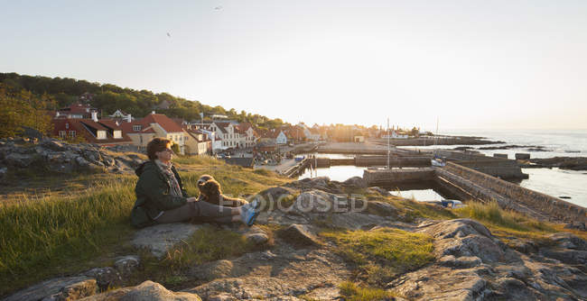 Mulher madura com cão sentado na costa em Bornholm, Dinamarca — Fotografia de Stock
