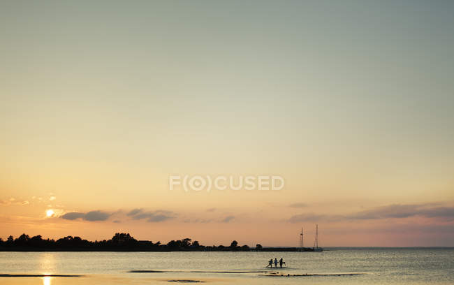 Mar al atardecer y siluetas de personas en las Indias Occidentales - foto de stock