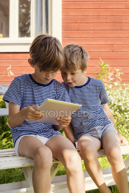 Brothers using digital tablet against building exterior — Stock Photo