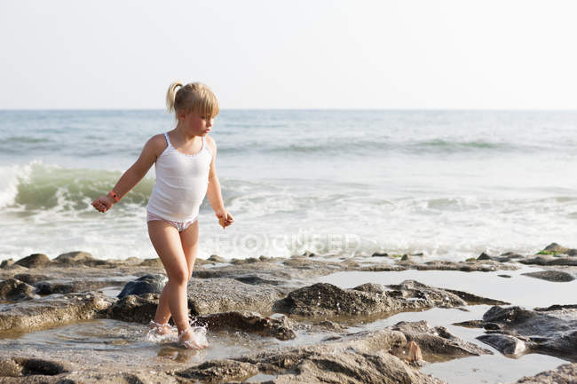 Menina loira andando na praia de rock — Fotografia de Stock