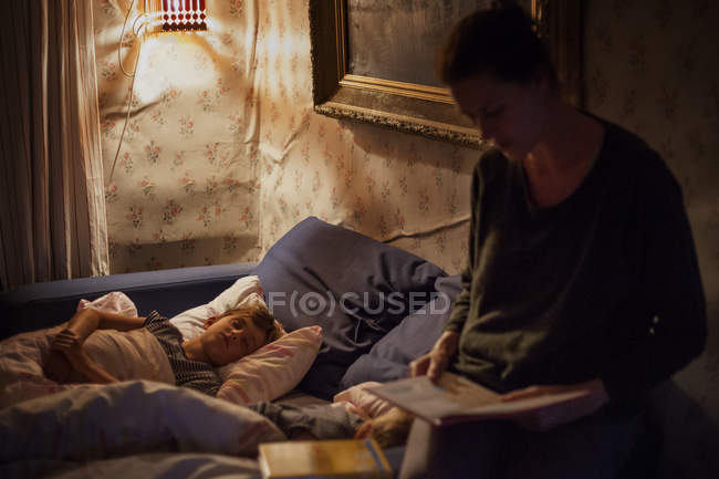 Madre che legge al figlio, concentrarsi sullo sfondo — Foto stock