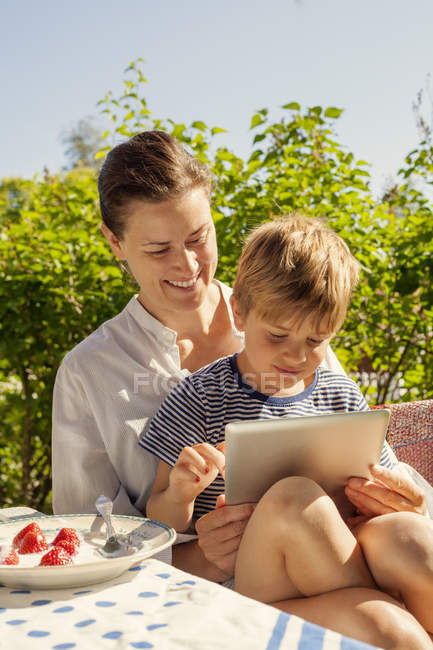 Portrait de fils et de mère en utilisant une tablette numérique dans le jardin — Photo de stock