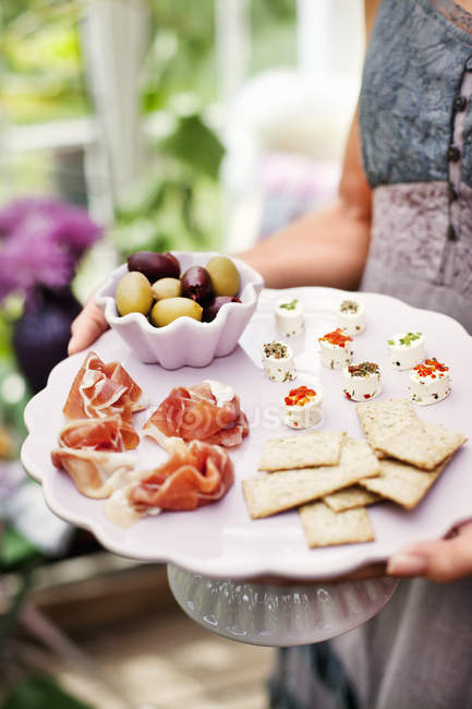 Woman holding plate with appetizers, focus on foreground — Stock Photo